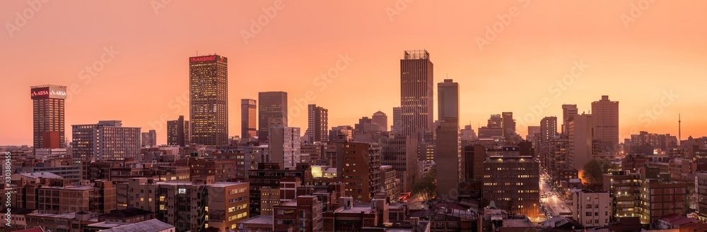 A beautiful and dramatic panoramic photograph of the Johannesburg city skyline, taken on a golden evening after sunset.